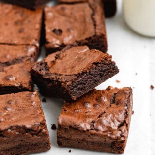 A close up of a batch of chewy brownies with one stacked on top of another with the inside texture showing on white countertop